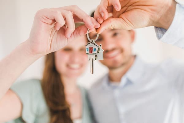A man and a woman holding a key in the shape of a house. Temporary Mortgage Rate Buydown.